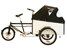 En trehjulig lastcykel med bakhjulet bakom sadeln. En stor lastlåda framför styret.